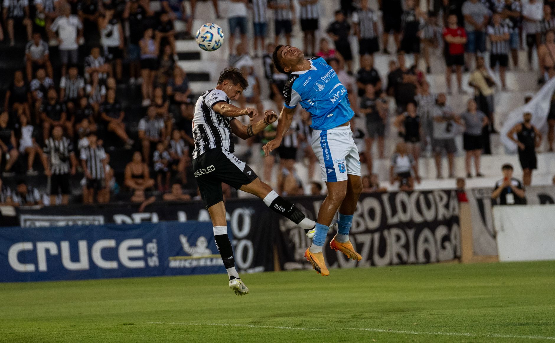 Two soccer players compete fiercely for the ball during a match, capturing an exciting sports moment.