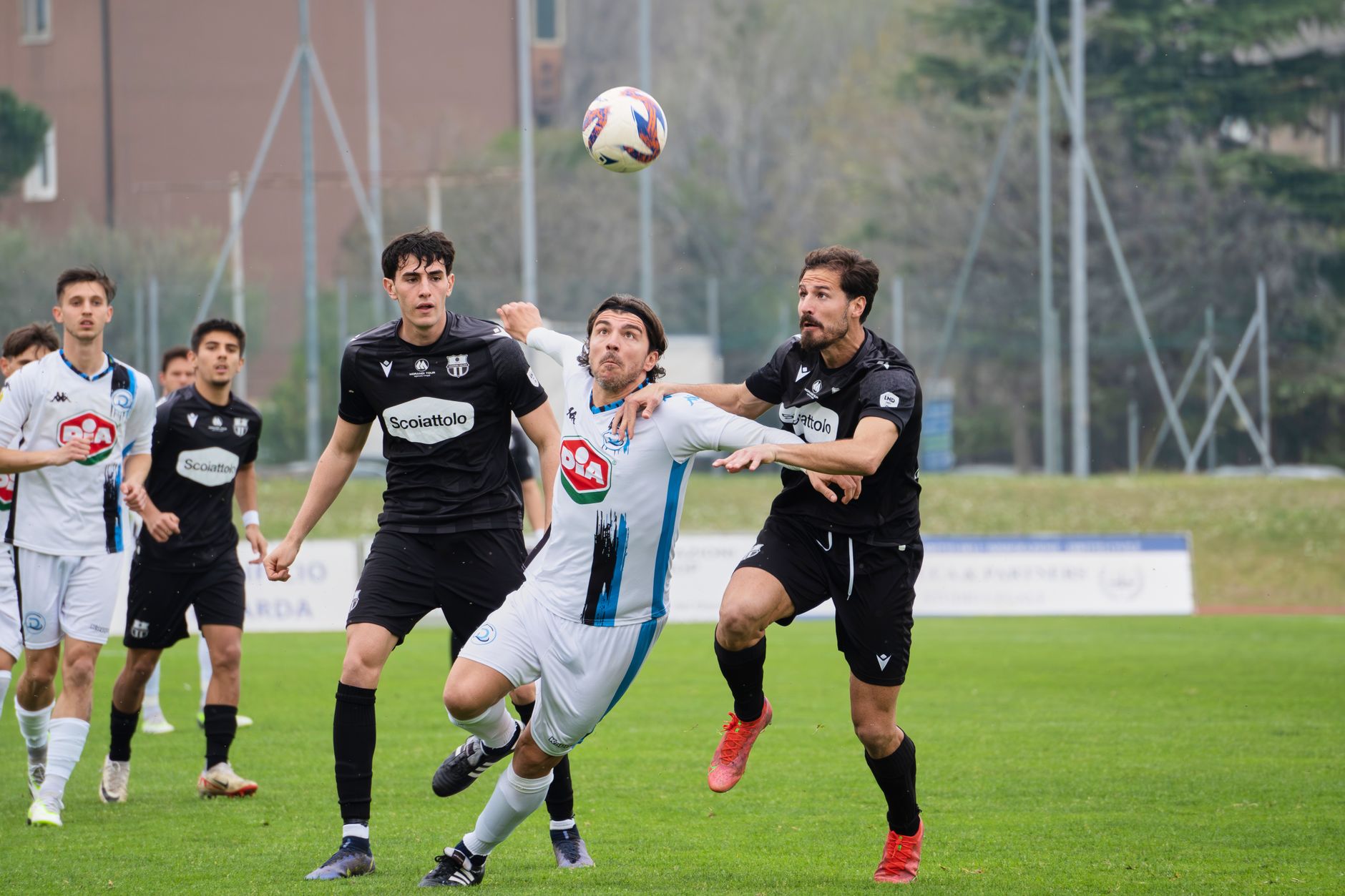 Players engage fiercely during a soccer match on a lush green field outdoors.
