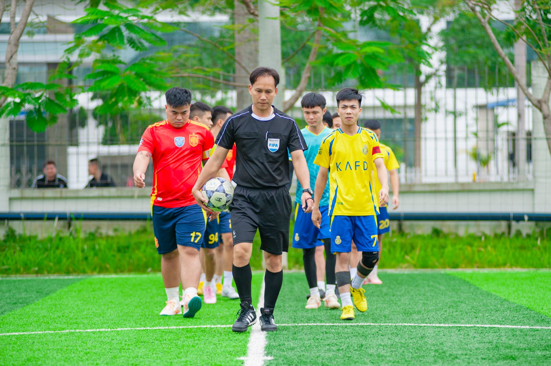 Soccer players and referee entering a field in Hanoi, Vietnam, showcasing teamwork and sportsmanship.
