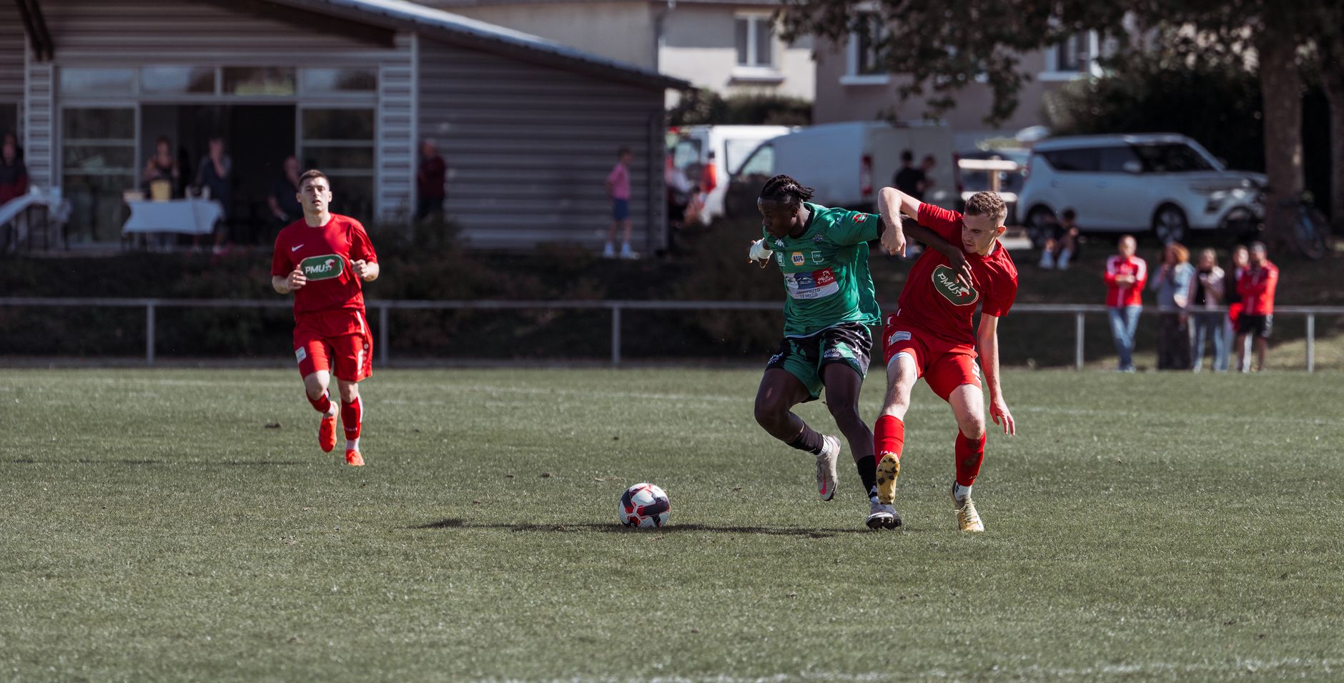 Players in action during an outdoor soccer match on a sunny day in France.