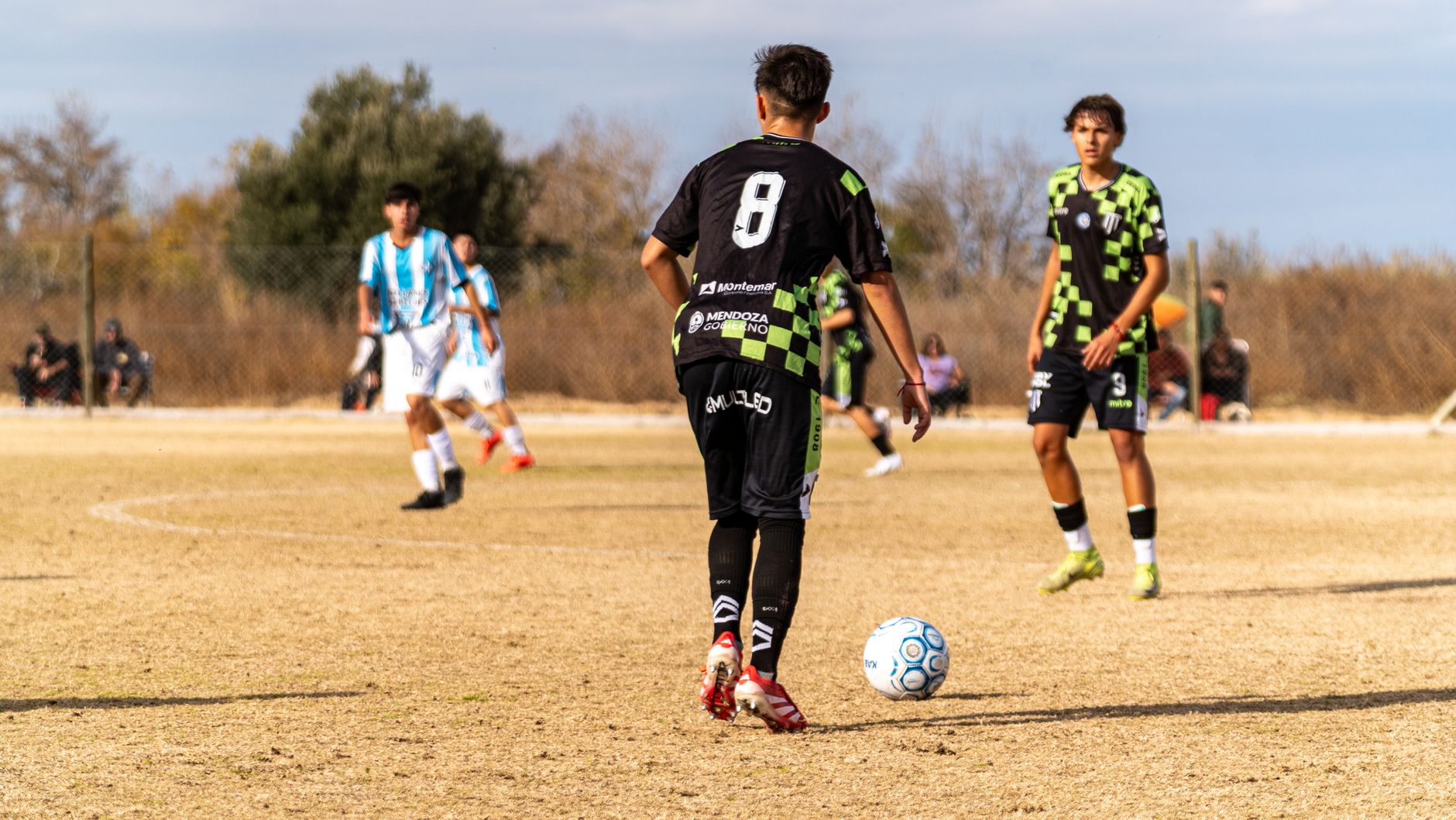 Boys playing soccer in a team match on a sunny day. Youth sports in action.