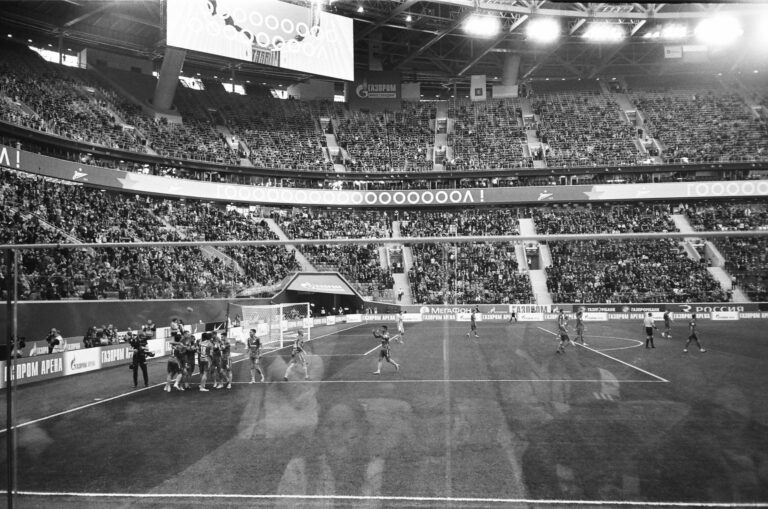 Through glass black and white football team standing together and congratulating each other with match win game in crowded stadium