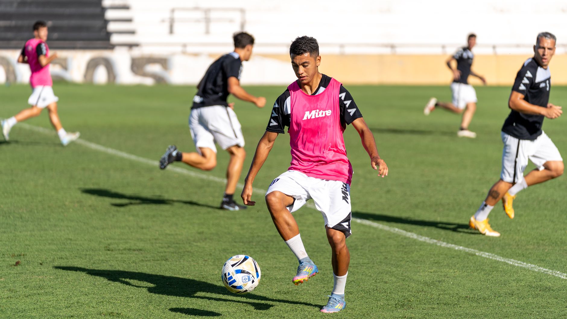 Soccer players training on a sunny day, focusing on dribbling and teamwork on a vibrant green field.