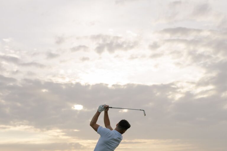 A golfer swings his club against a dramatic cloudy sky, capturing the essence of the sport.