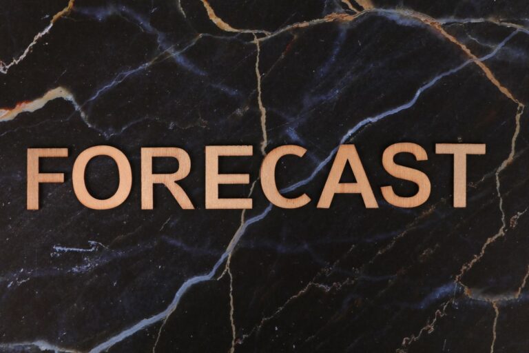 The word 'FORECAST' in wooden letters on a dark marble background.