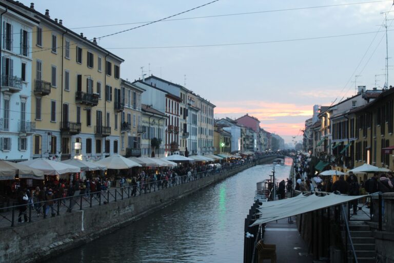 Scenic evening view of Naviglio Grande canal in Milan with vibrant street life.