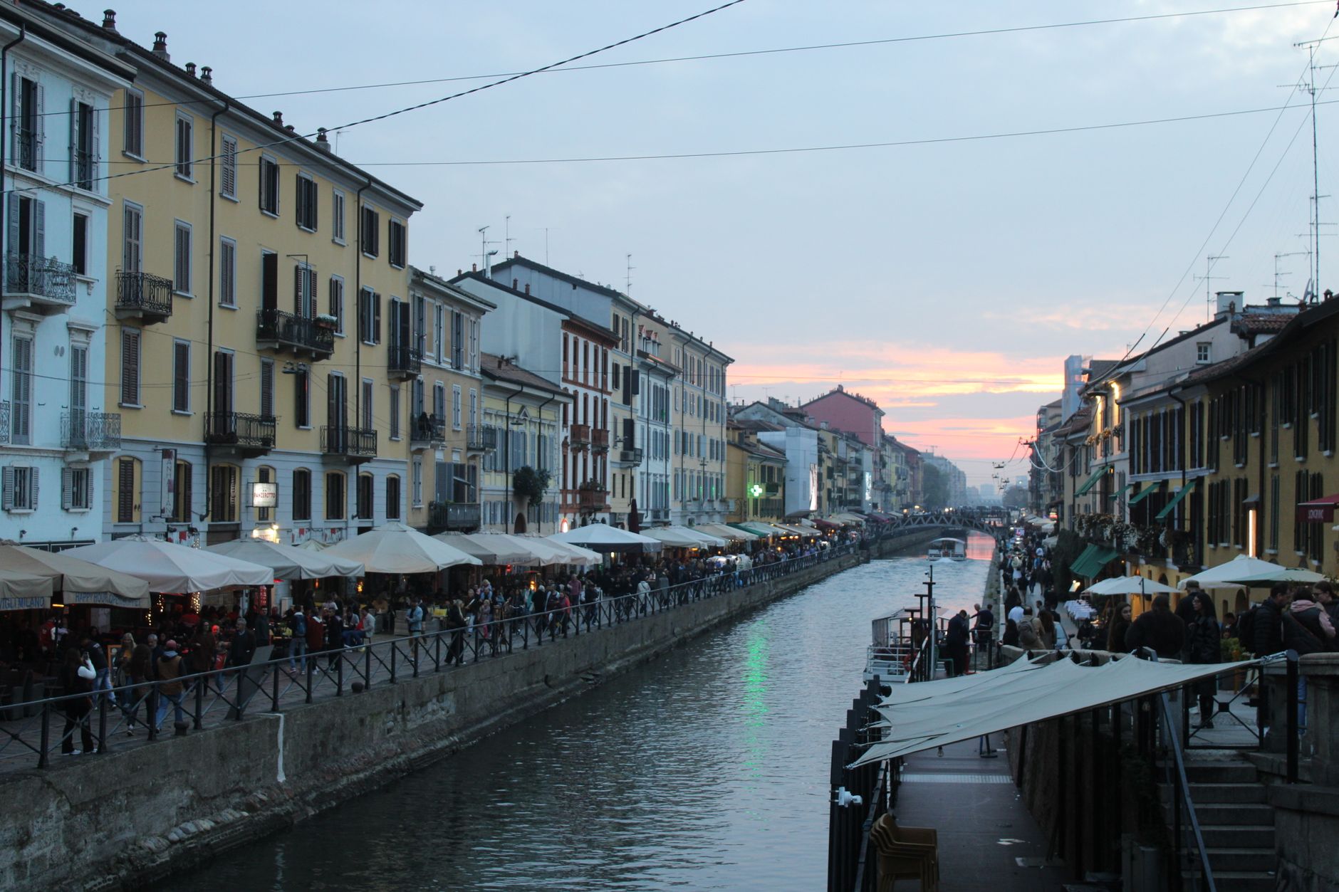 Scenic evening view of Naviglio Grande canal in Milan with vibrant street life.