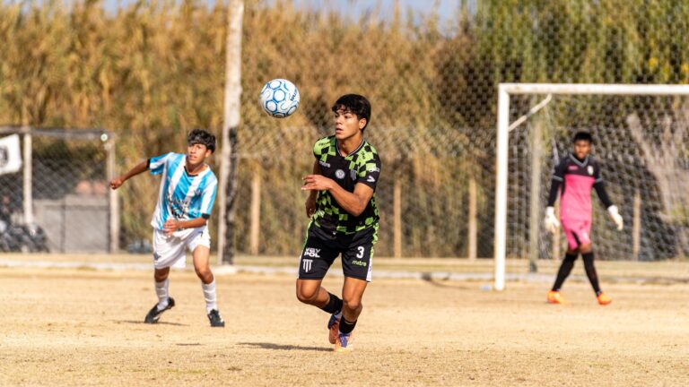 Dynamic action shot of teenagers playing soccer outdoors on a sunny day.