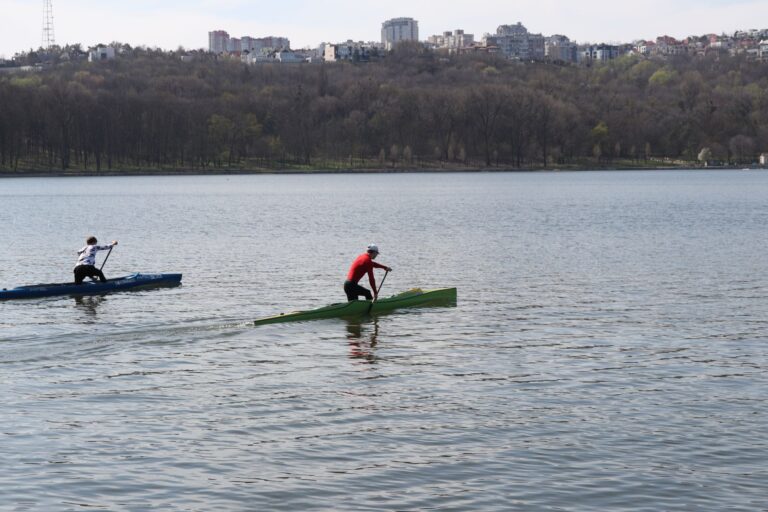 Canoeists racing on a serene lake in Chișinău, showcasing outdoor sports and nature.
