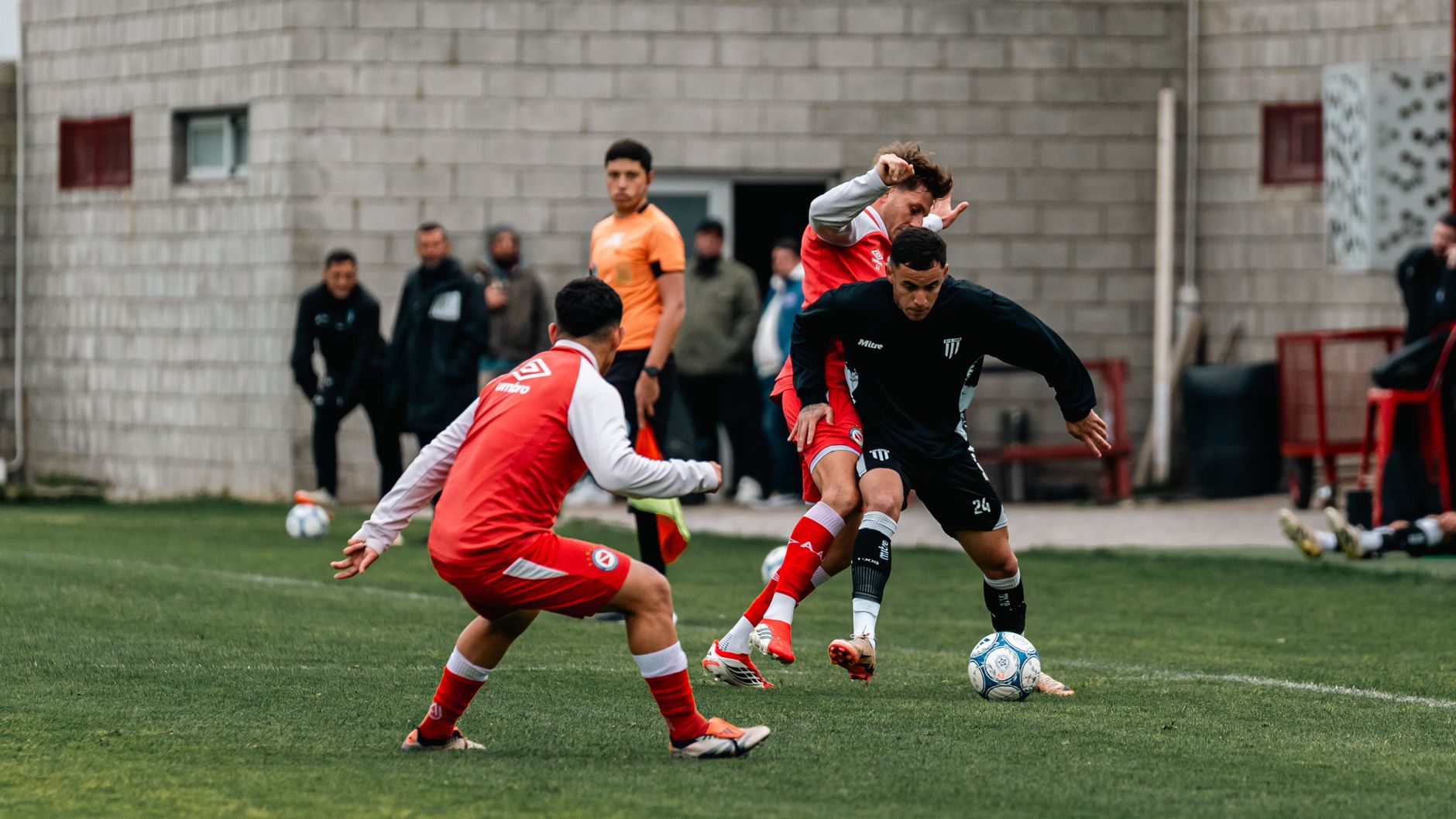 Players in red and black uniforms compete fiercely during a soccer match.