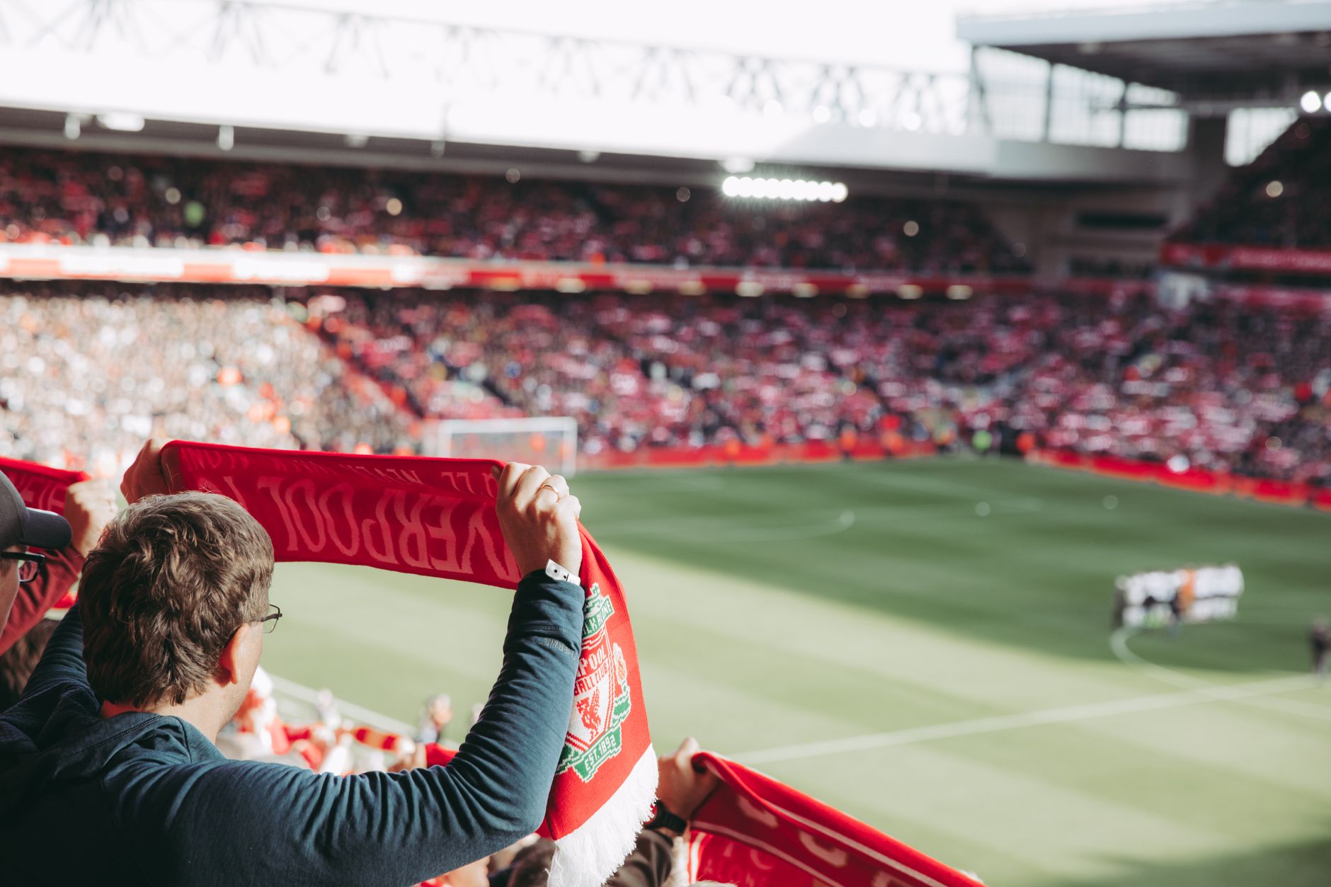 Passionate soccer supporters with scarves in Anfield Stadium, capturing the thrill of the game.
