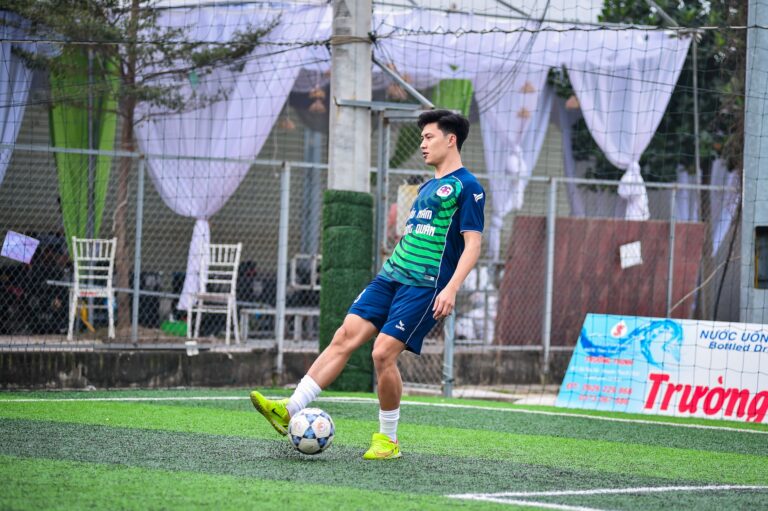 A young football player practicing on an artificial turf field in Hanoi, Vietnam.