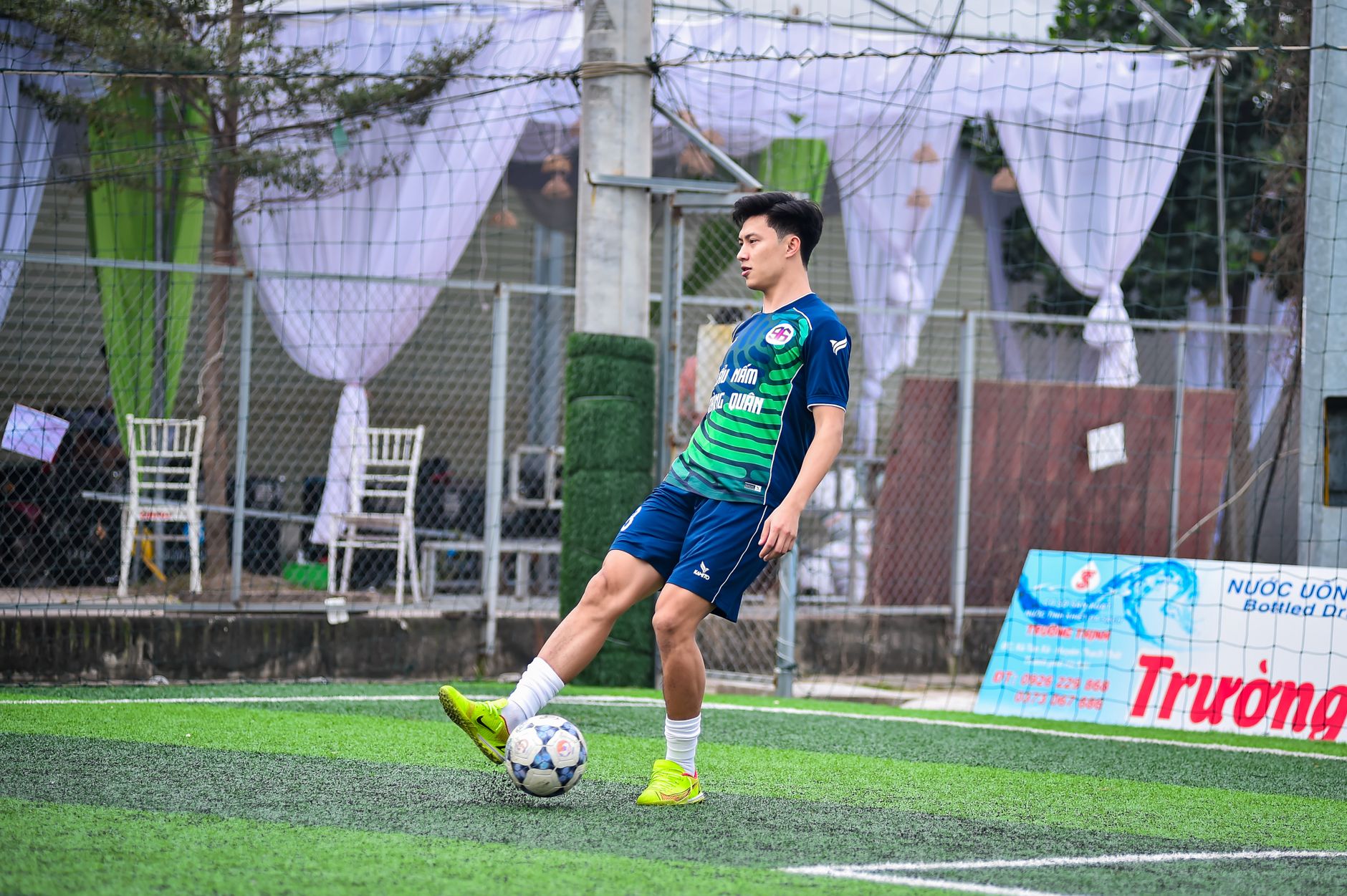 A young football player practicing on an artificial turf field in Hanoi, Vietnam.