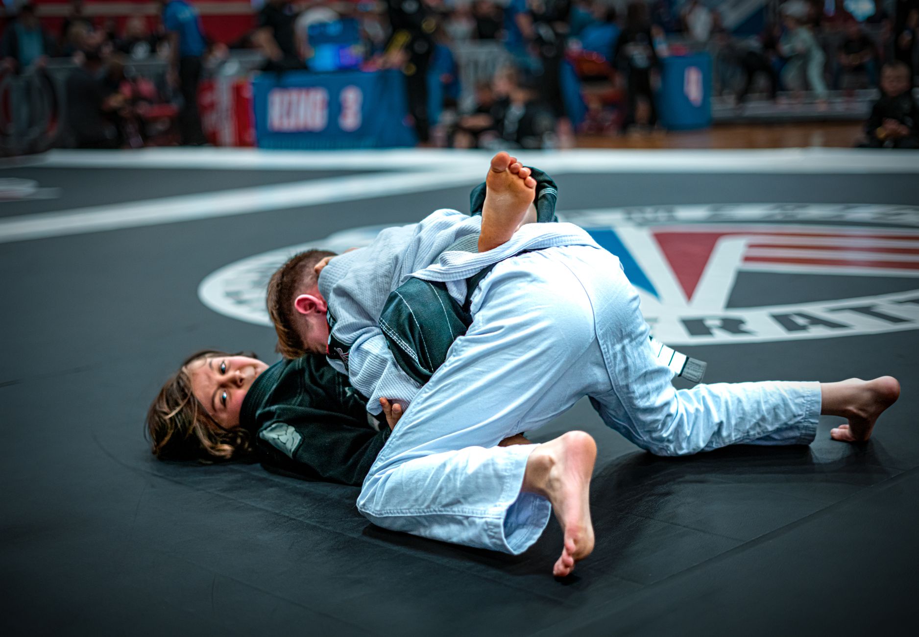 Two teenagers in martial arts sparring on a competition mat, showcasing skill and determination.