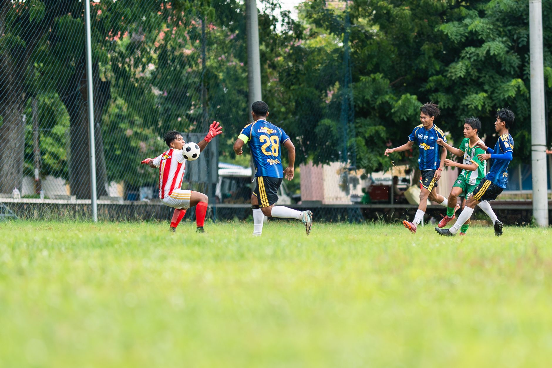 Action-packed youth soccer game with goalie and players in dynamic pursuit of the ball.