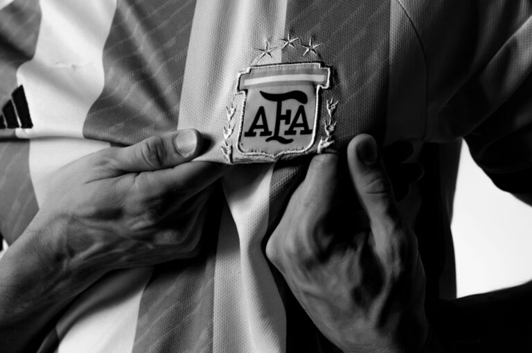 A close-up view of hands holding the Argentina football jersey with AFA emblem, in black and white.