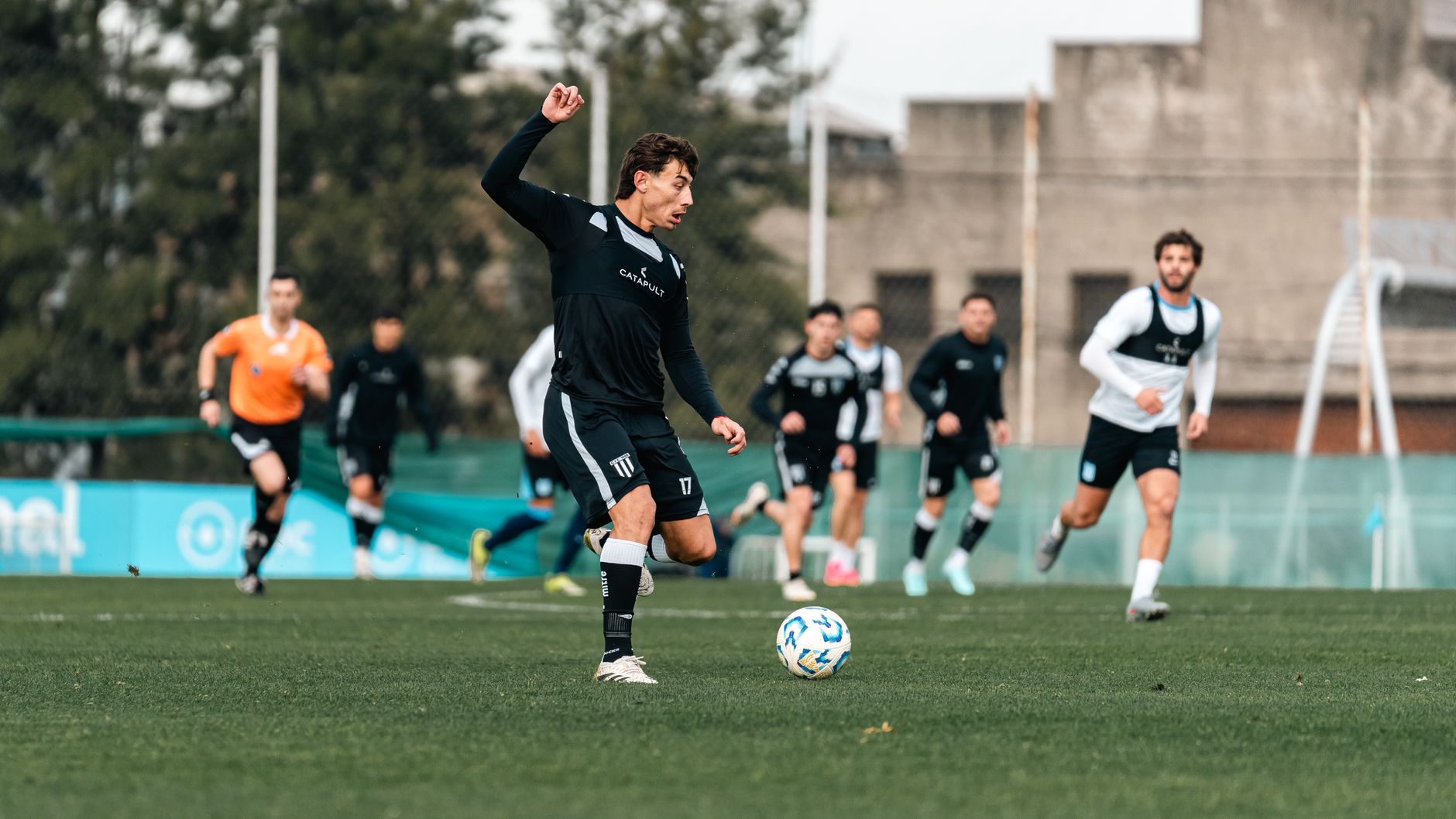 Professional soccer players in action during a training session on a field.