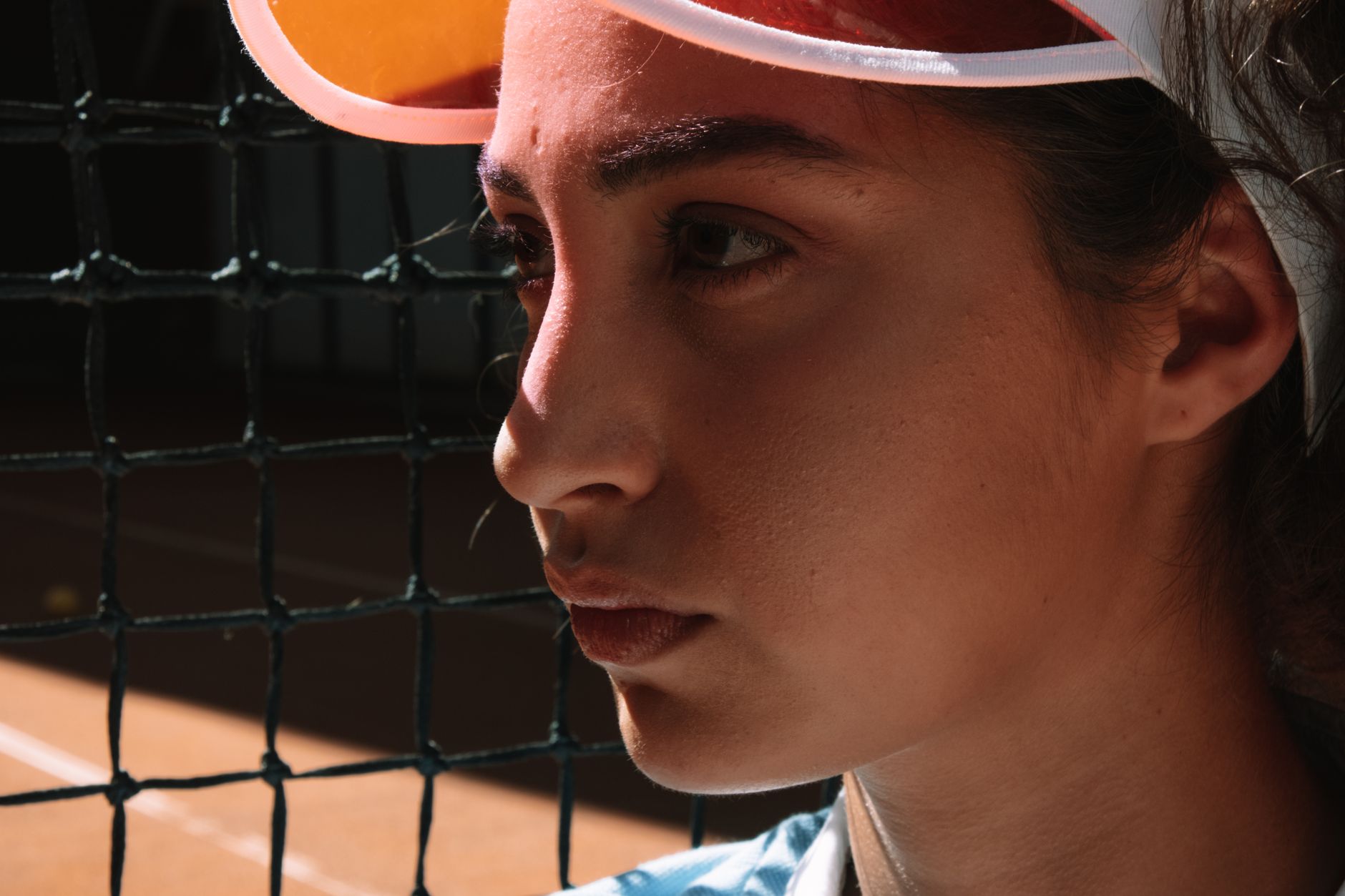 Close-up of a female tennis player in deep focus on the court next to the net.