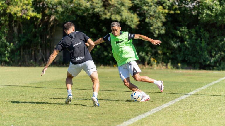 Two soccer players in action during a training session on a sunny day, showcasing agility and skill.