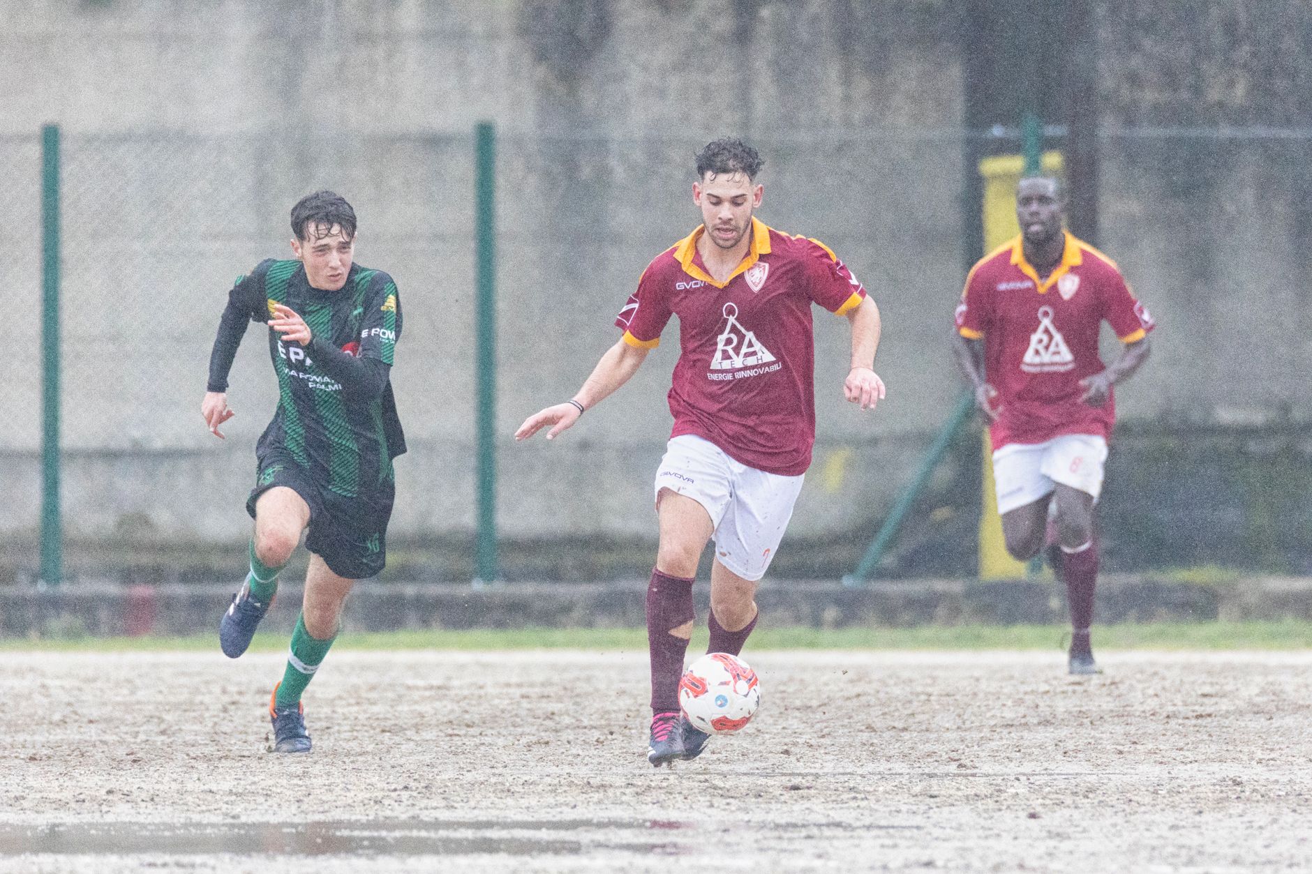 Athletes play soccer in rainy Delianuova, Calabria, Italy, showcasing teamwork and dedication.