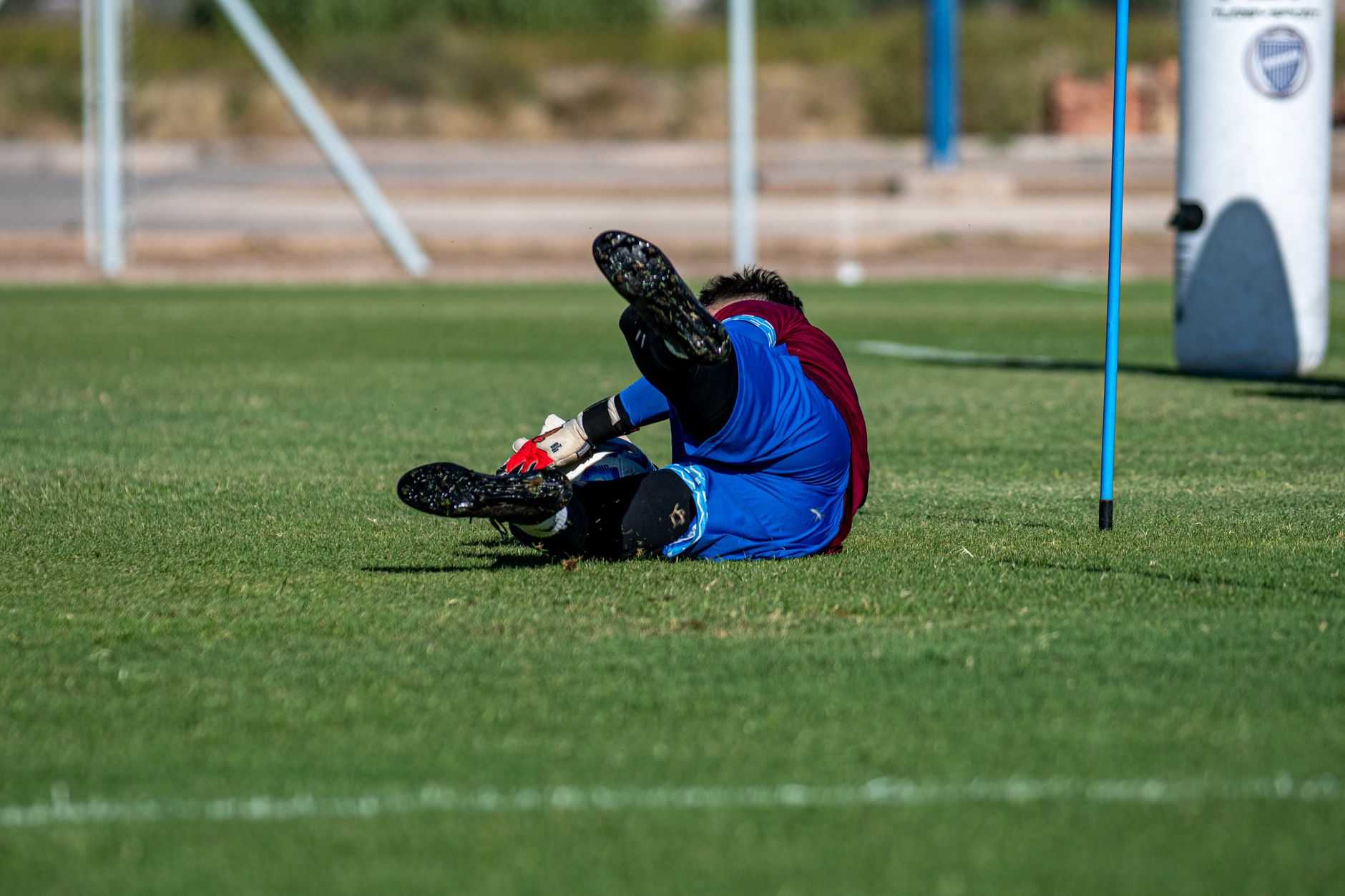 Soccer player dives during training, showcasing agility and skill on grass field.