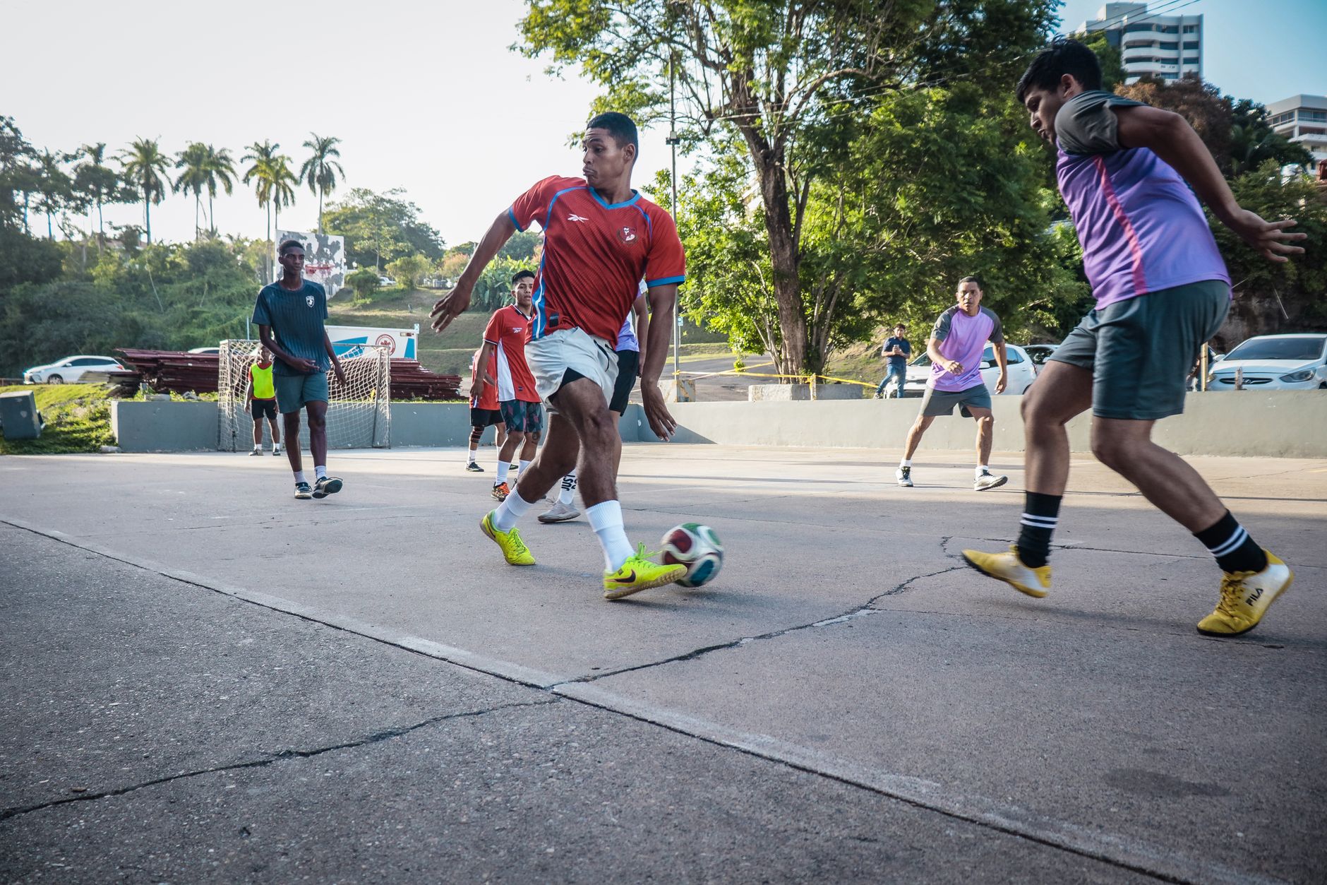 Amateur players compete in an intense street football match on a sunny day.