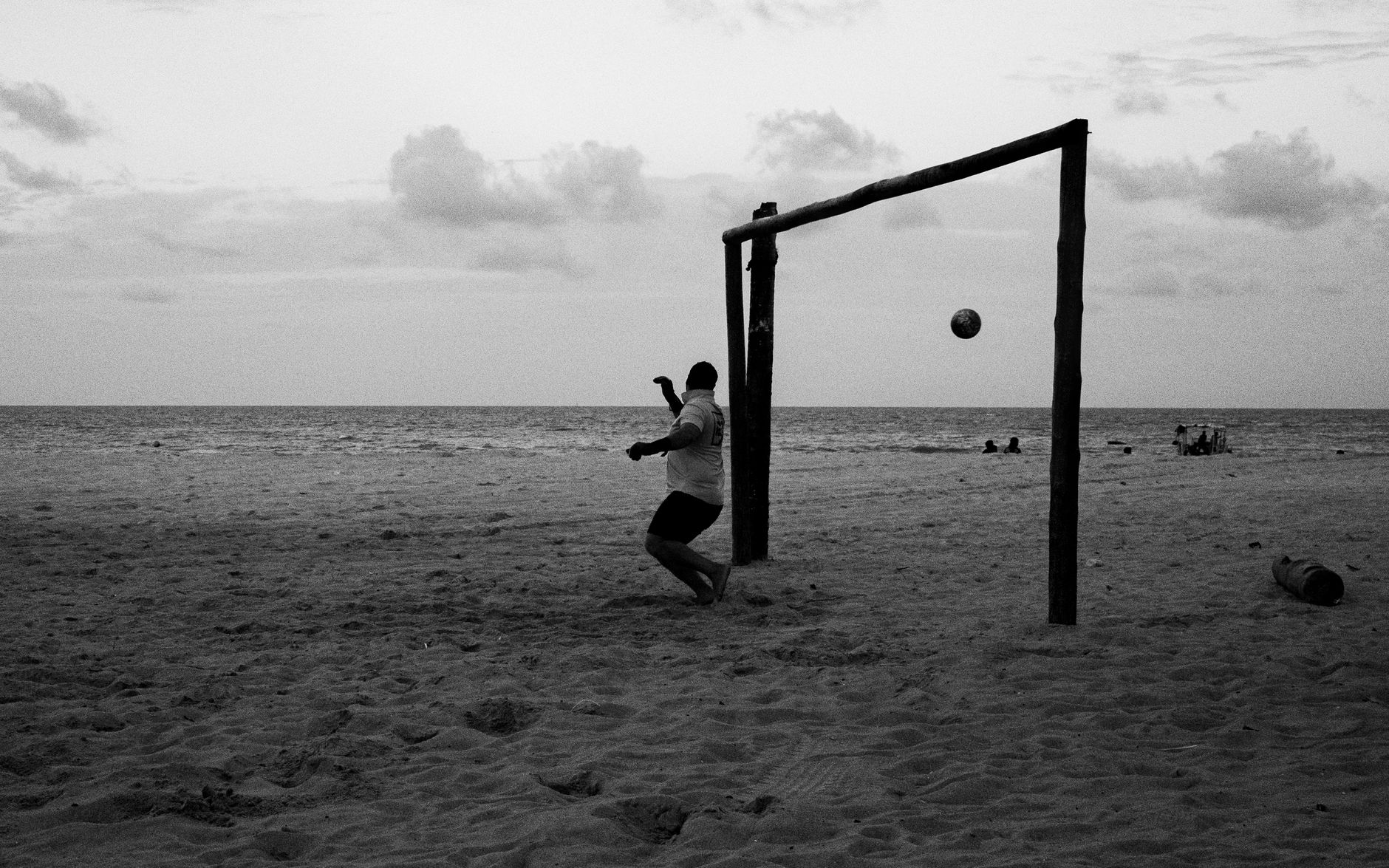 A monochrome shot of a soccer game on a beach in Natal, Brazil during twilight.