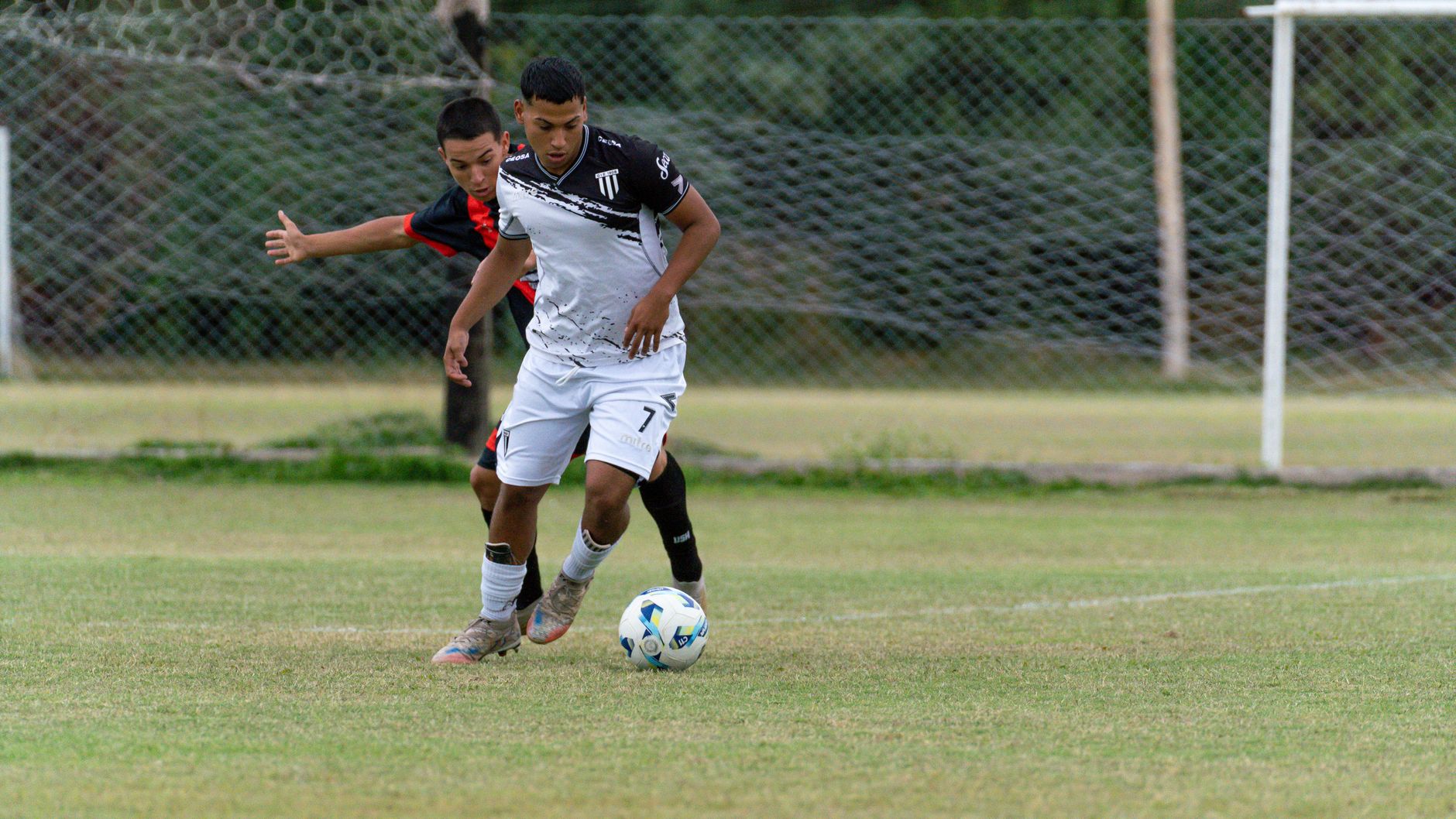 Two young soccer players competing fiercely during a match on a grass field.