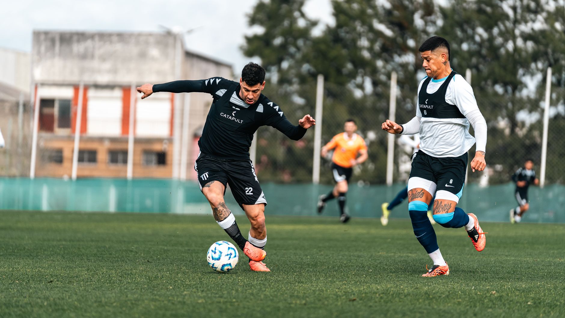 Two soccer players in mid-action during a competitive training session outdoors.