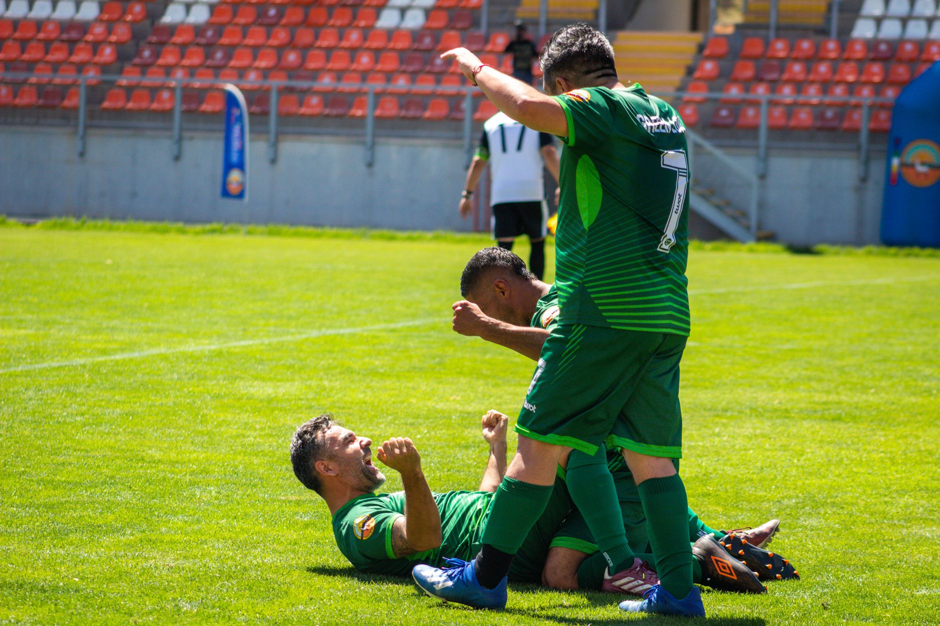 Dynamic shot of soccer players celebrating a goal during a daytime match.