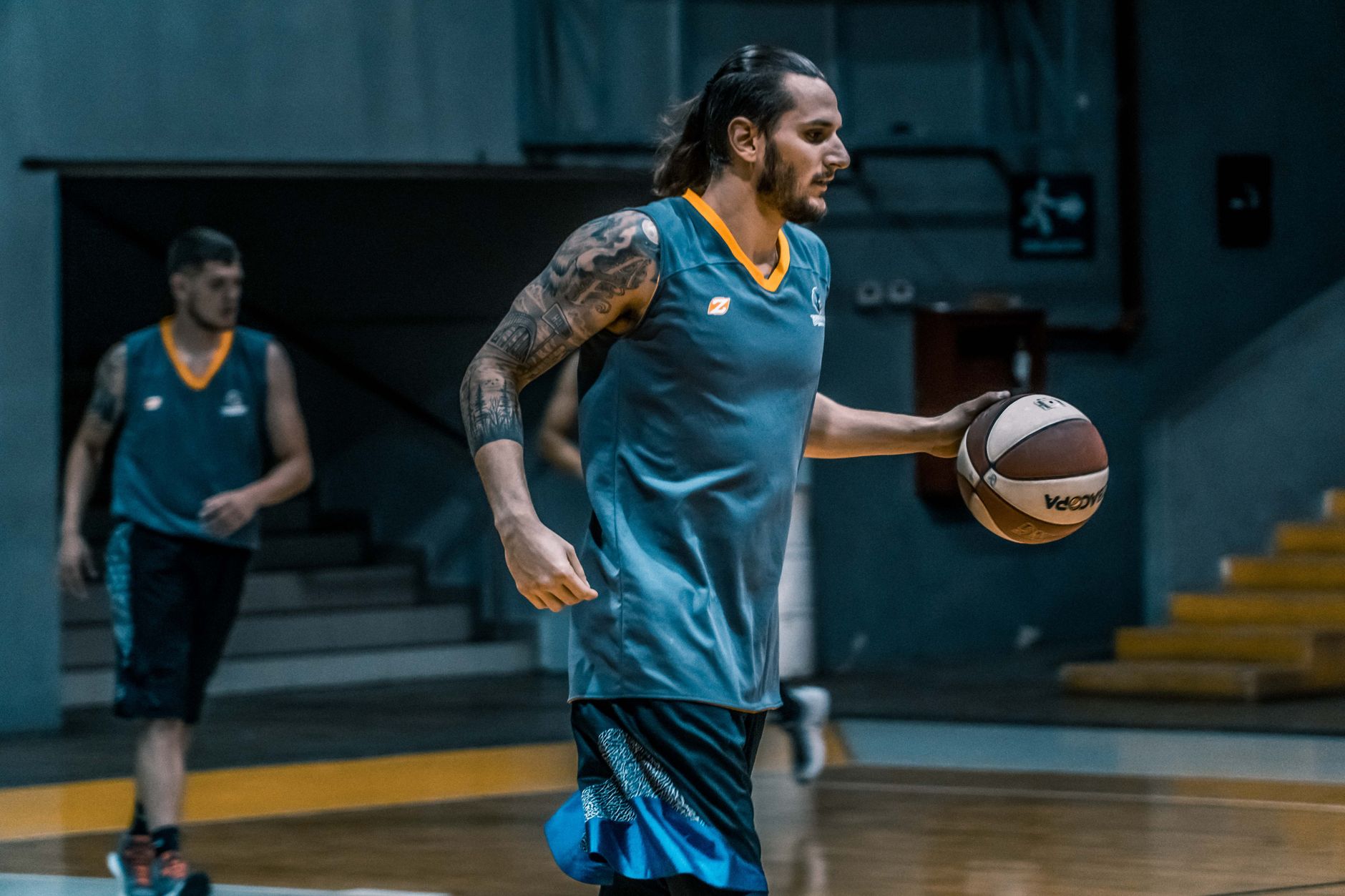 Athletes focused on basketball training indoors, emphasizing teamwork and skills.