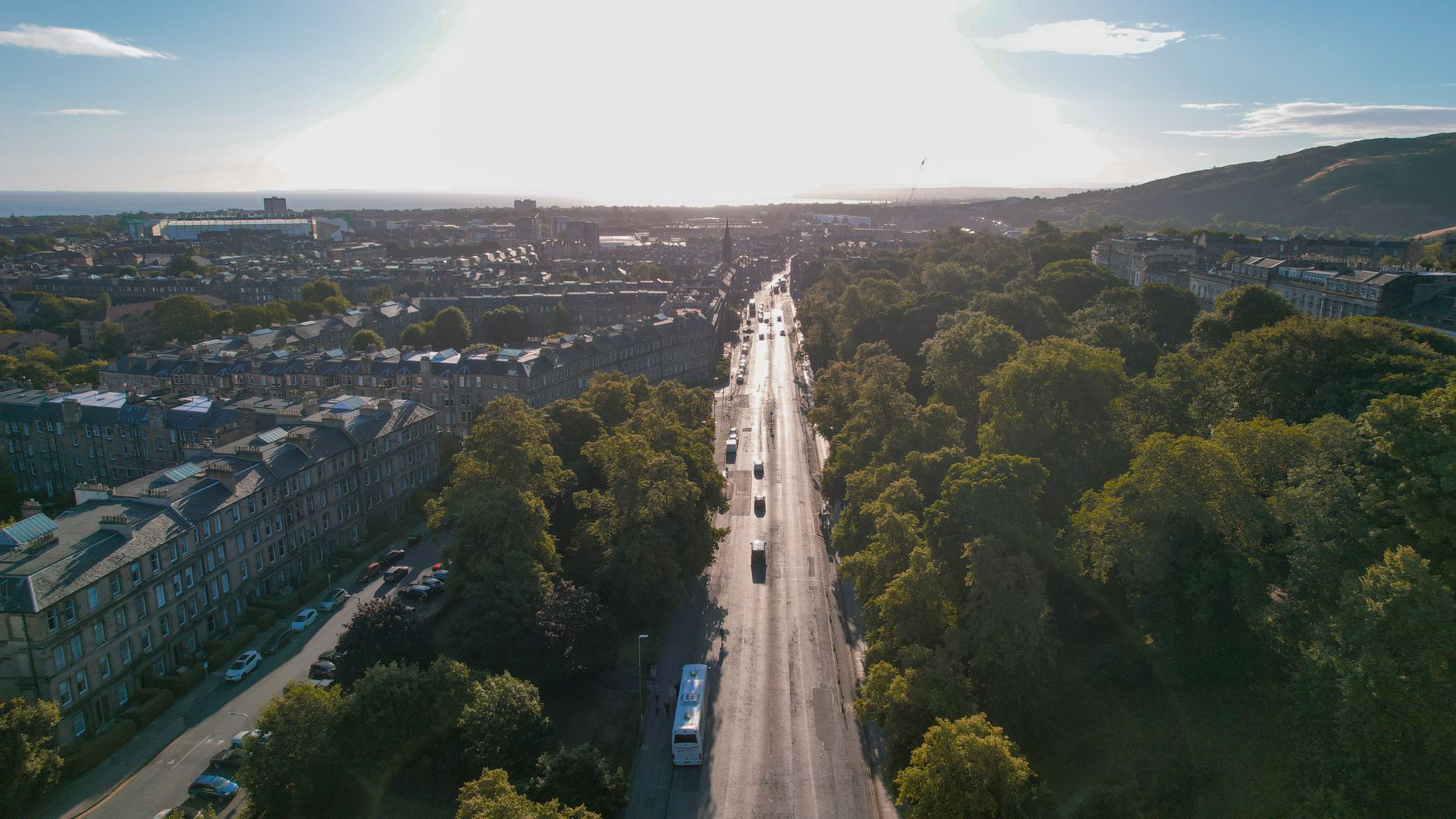Scenic aerial view of a road in Edinburgh, Scotland with trees and buildings at sunset.