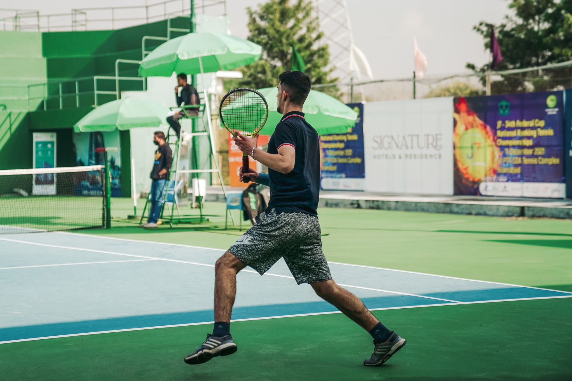 A male athlete playing tennis on a sunny day in Islamabad, Pakistan.