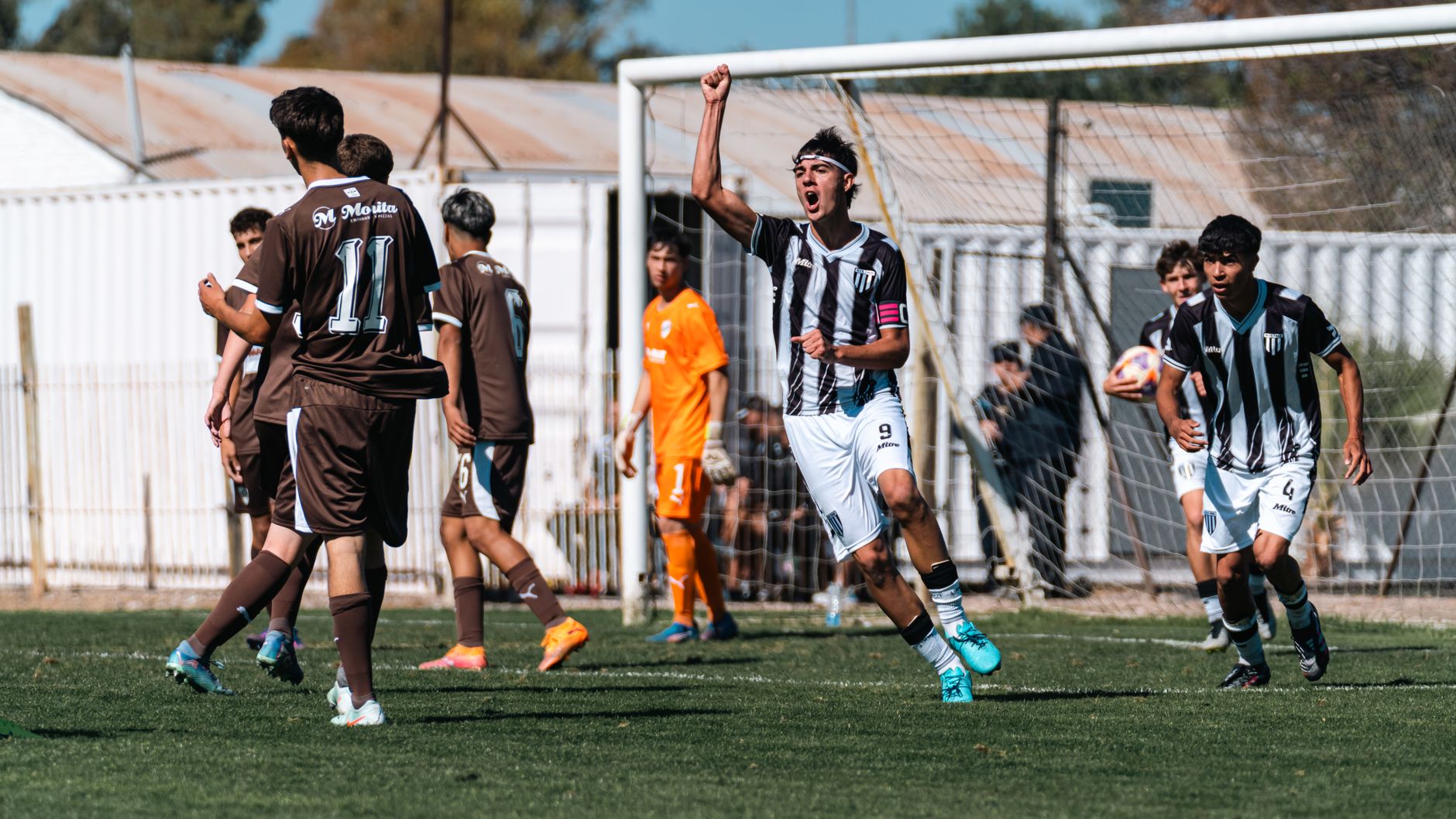 Teen soccer player celebrates scoring a goal during an intense youth match.