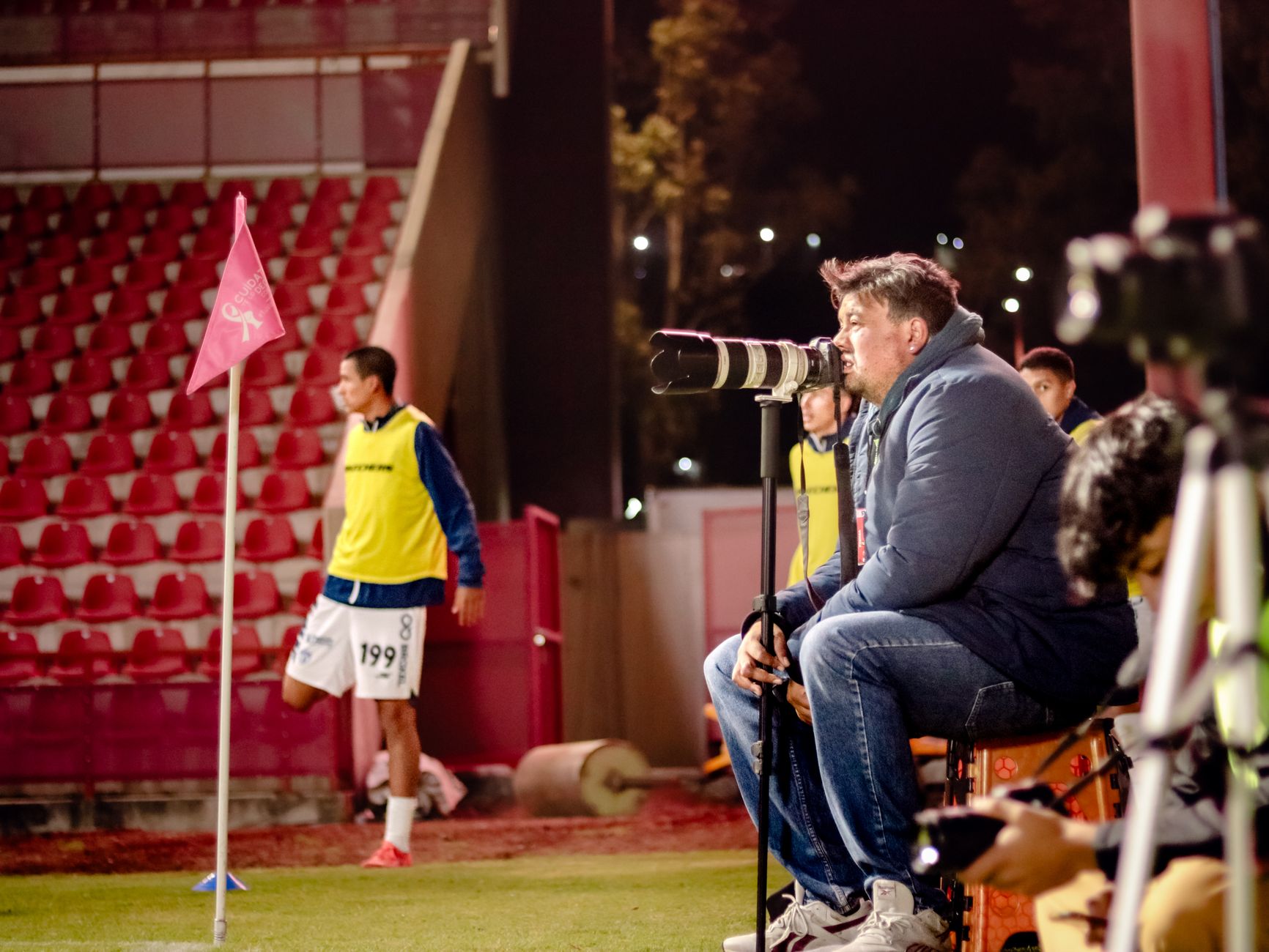 Soccer coach intensely watches game at night stadium, focused on strategy.