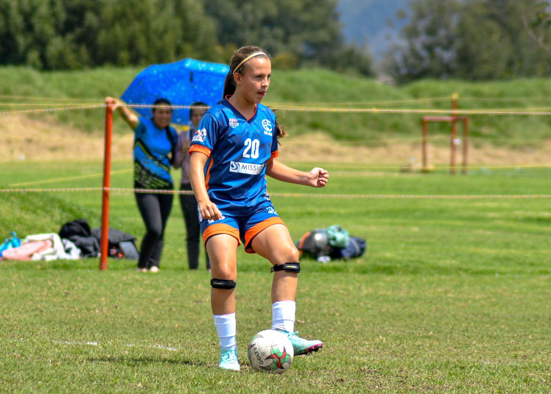 Teen girl playing soccer on a sunny day, showcasing determination and athleticism.