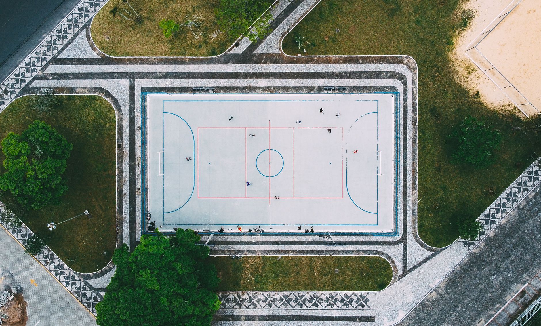 Drone shot capturing an outdoor sports court in Araranguá, Brazil with players on the field.