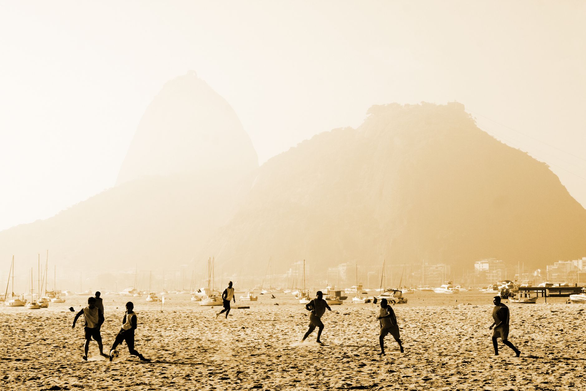 Dynamic beach soccer game with Sugarloaf Mountain in Rio de Janeiro.
