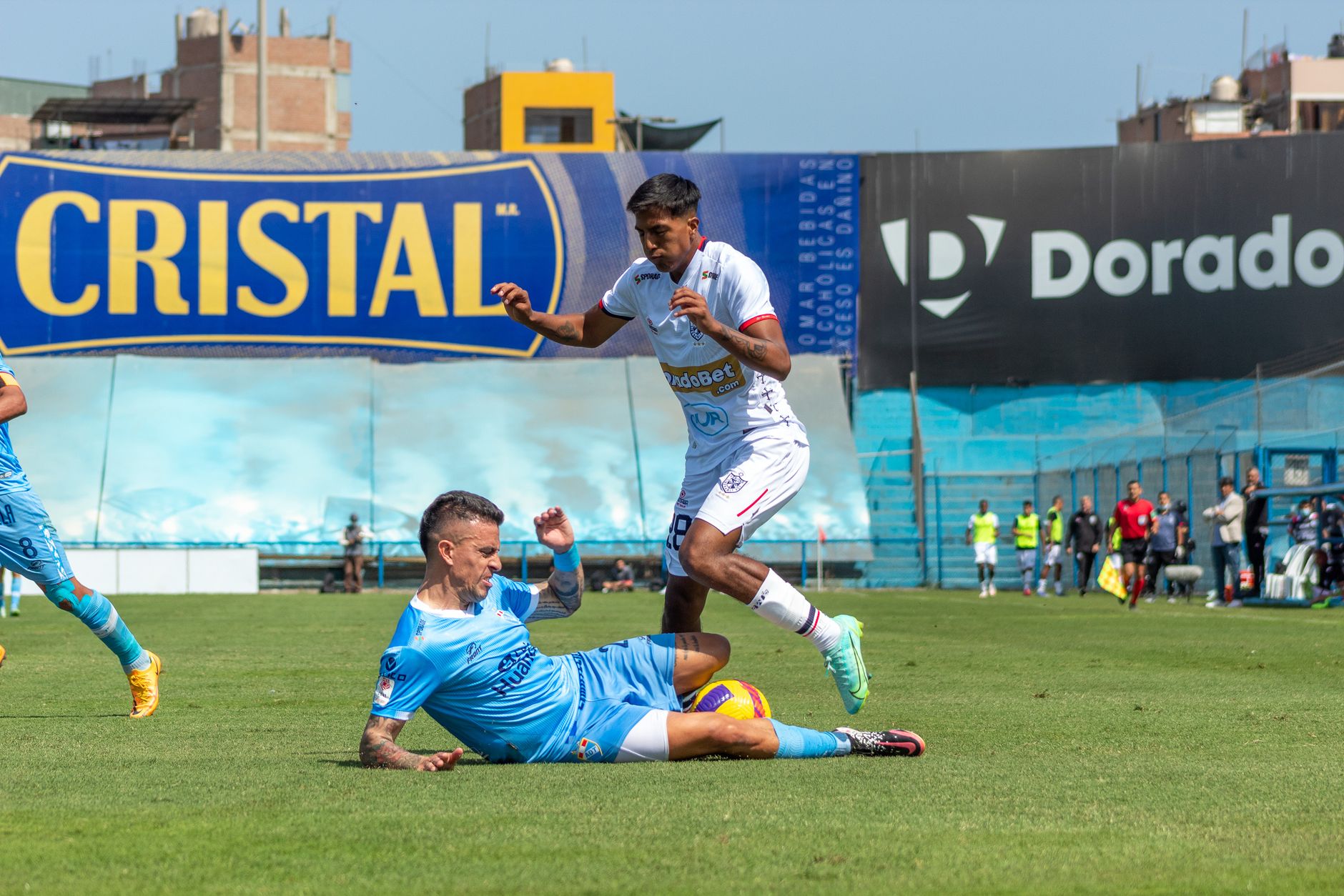 Dynamic soccer action during a competitive match, capturing a tackle between players.
