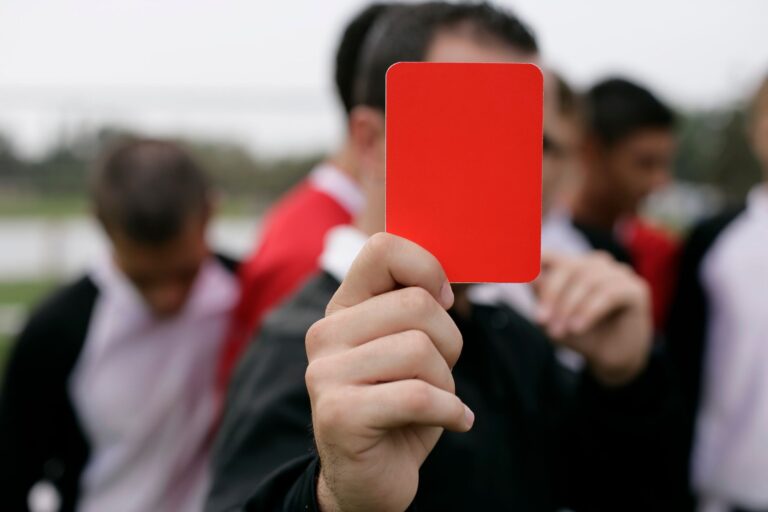 Referee showing a red card to players during an outdoor soccer game.