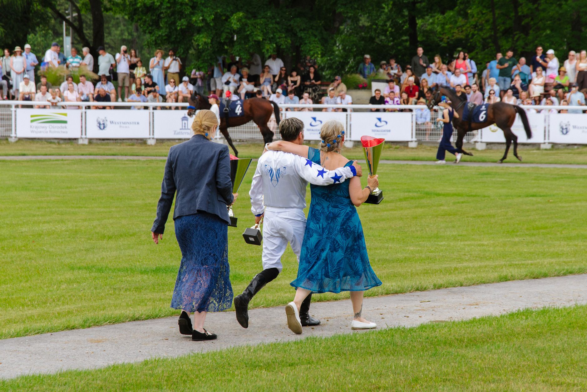A jockey and supporters celebrate a victory at a lively horse racing event outdoors.
