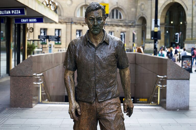 Bronze walking man statue in downtown Newcastle, England street view.
