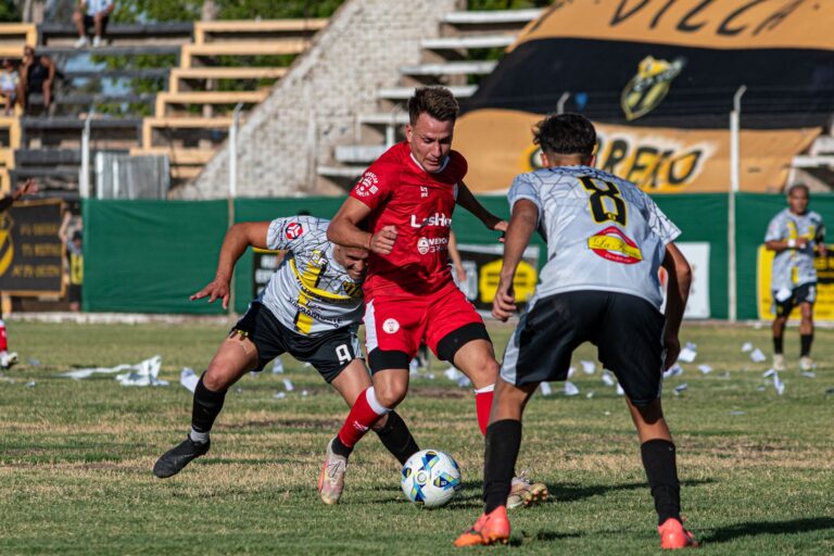 Three male soccer players competing intensely on a grassy field.