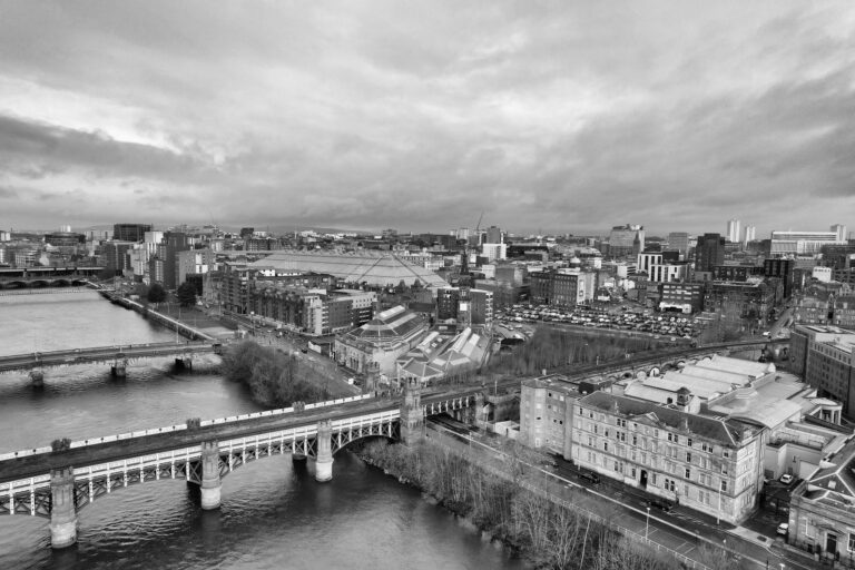 Aerial black and white cityscape of Glasgow, showcasing the River Clyde and iconic architecture.