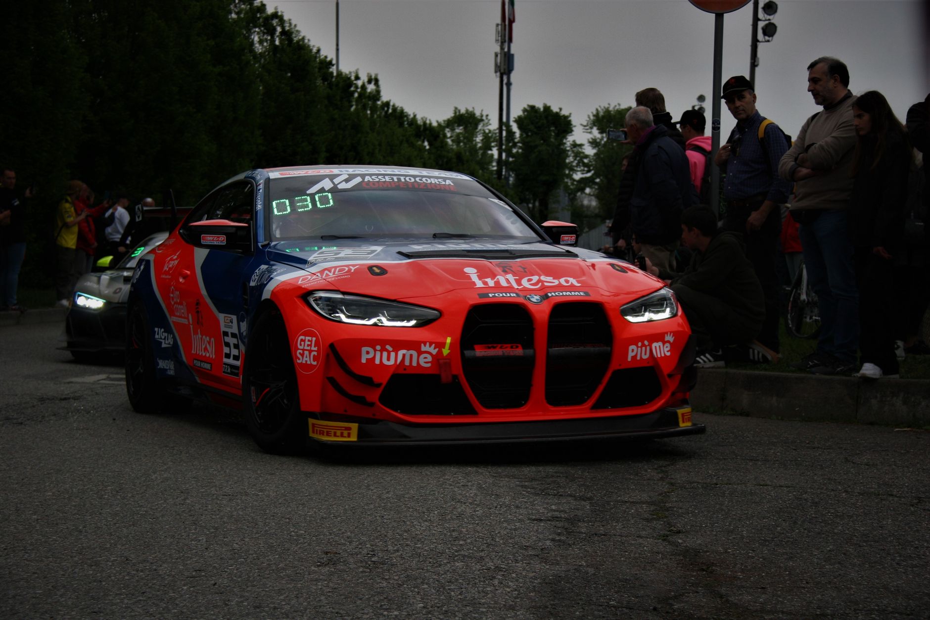 A sleek BMW M4 racecar on city streets during a motorsport event in Monza, Italy.
