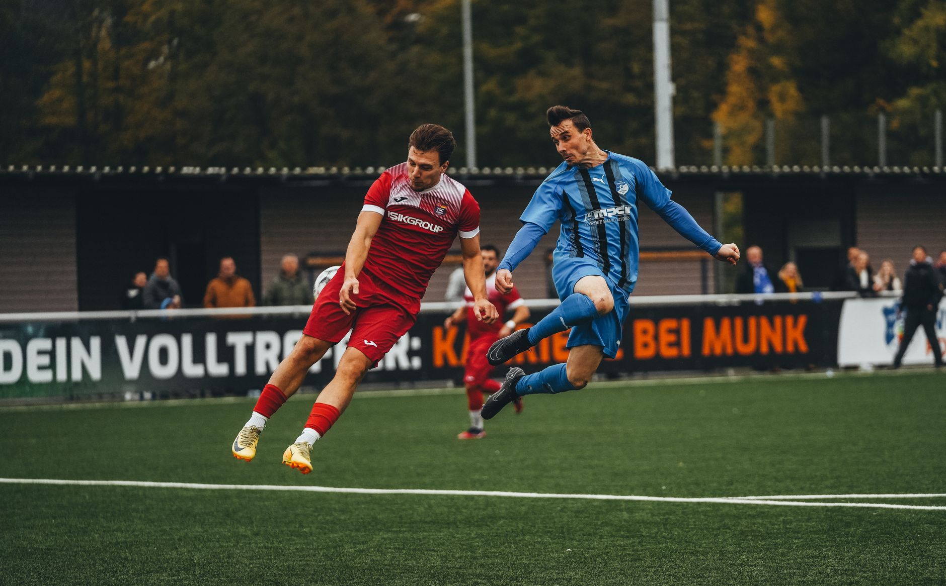 Two soccer players compete fiercely during a match on a green field.