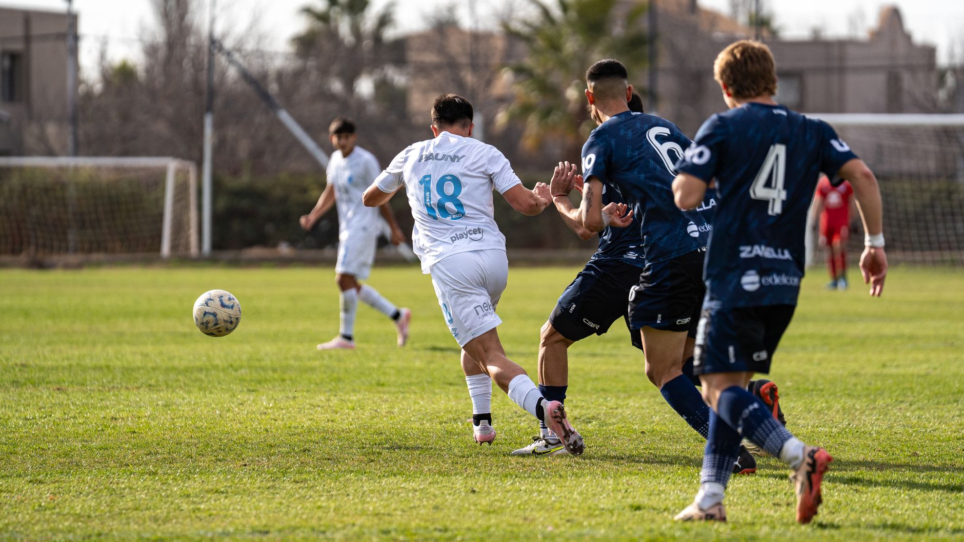 Football players in action on a sunny day, showcasing teamwork and competition.