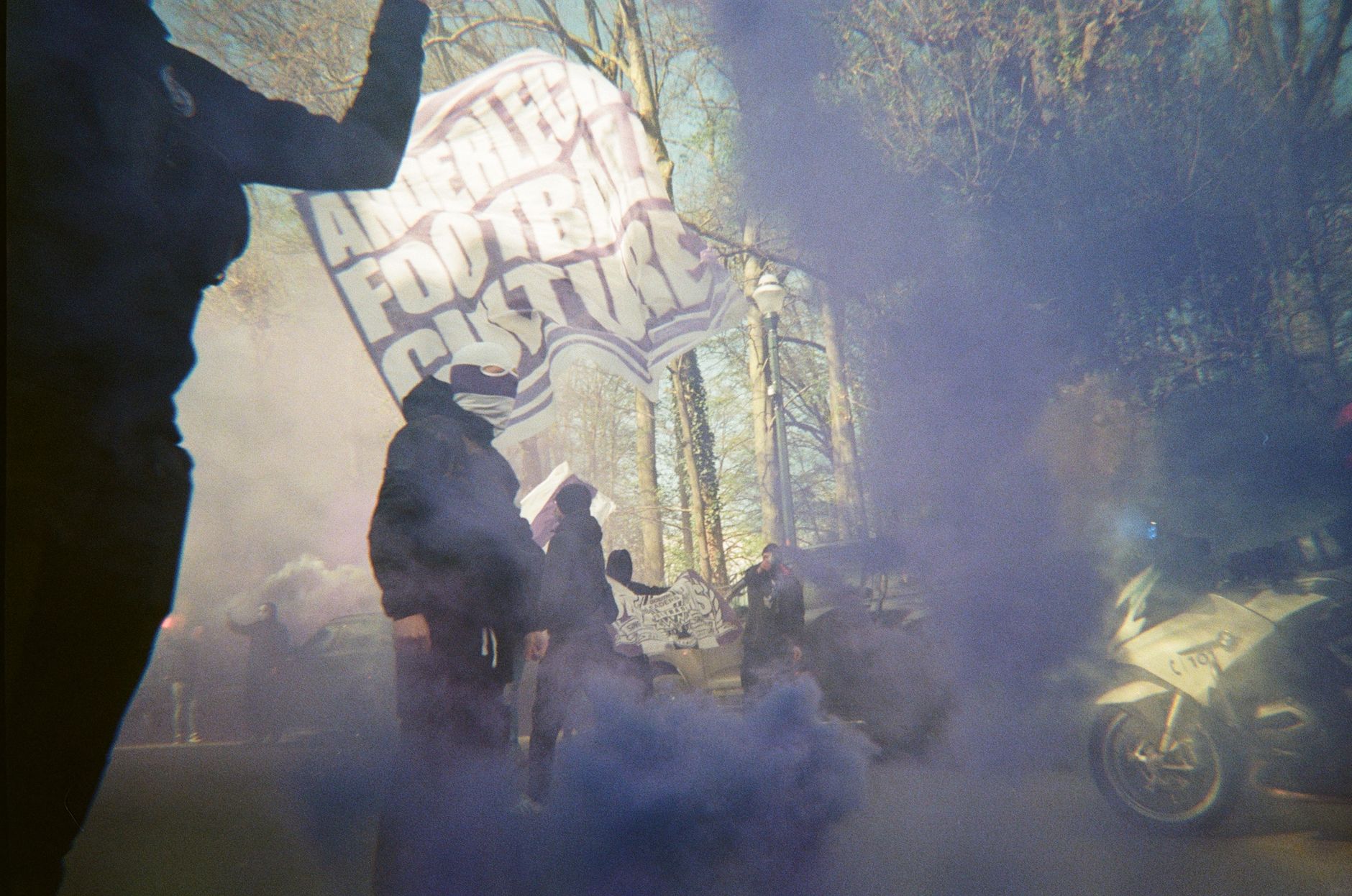 Protesters with banners and smoke on a street, creating a dynamic atmosphere.