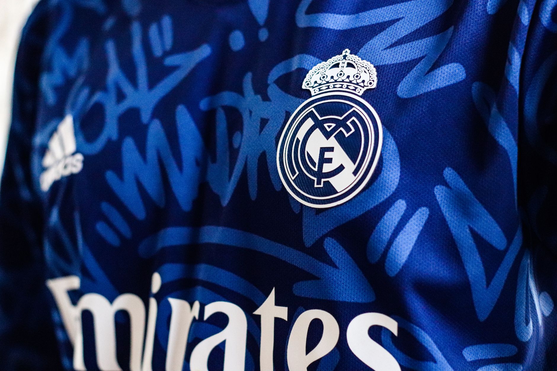 Close-up view of a blue Real Madrid soccer jersey featuring the team's logo and design elements.