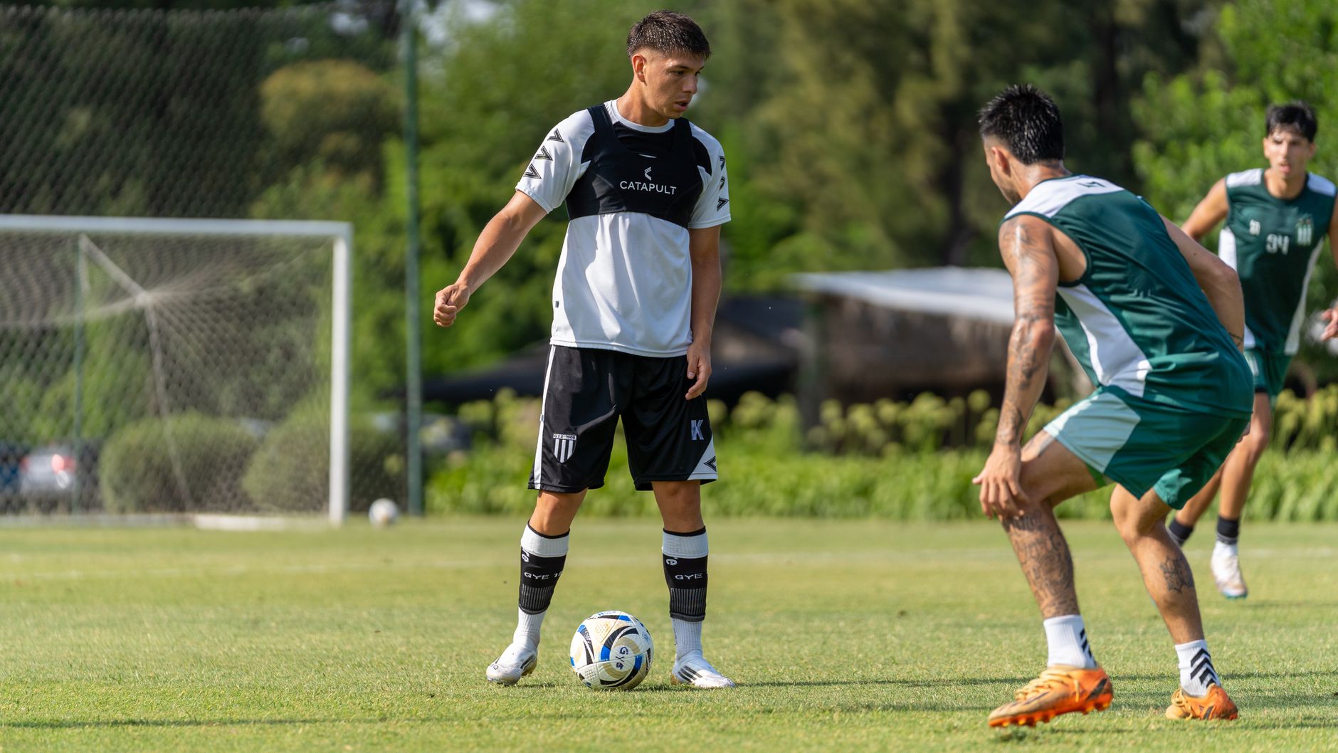 Two soccer players face off on a sunny outdoor field, preparing for a match.